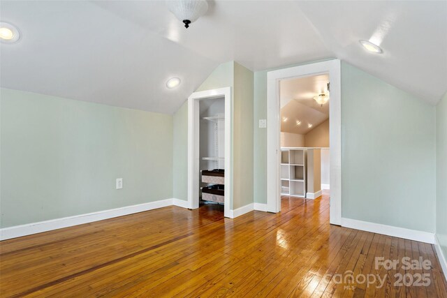 additional living space with hardwood / wood-style flooring and vaulted ceiling