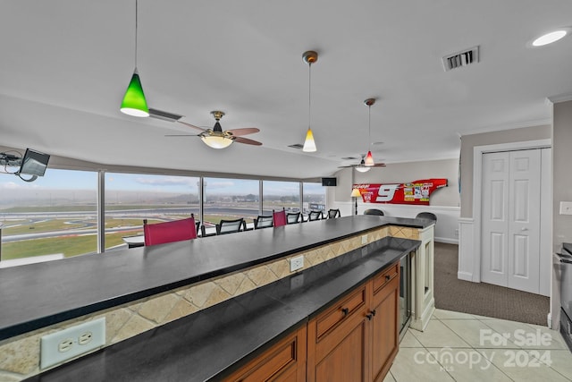 kitchen with ornamental molding, ceiling fan, hanging light fixtures, and light tile patterned floors