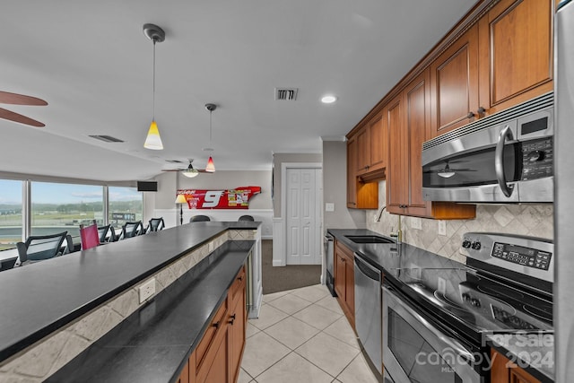 kitchen with appliances with stainless steel finishes, light tile patterned floors, pendant lighting, ceiling fan, and sink