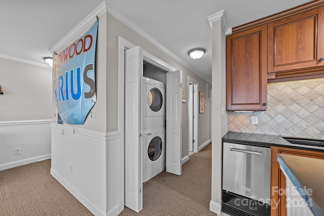 clothes washing area featuring ornamental molding, stacked washer / dryer, laundry area, wainscoting, and carpet