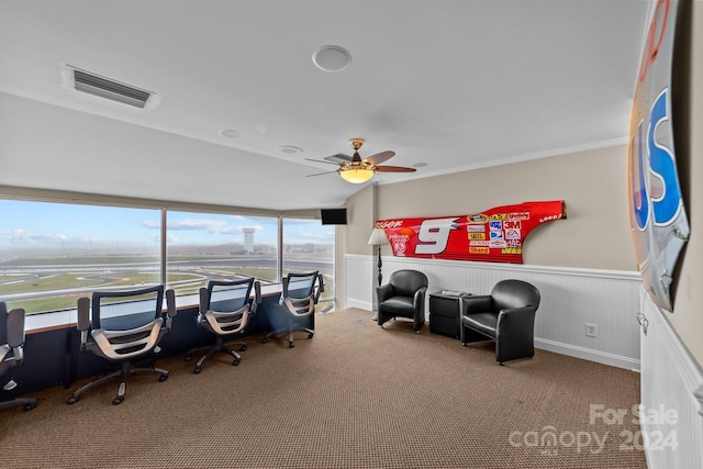 carpeted home office with visible vents, ornamental molding, a ceiling fan, and a wainscoted wall