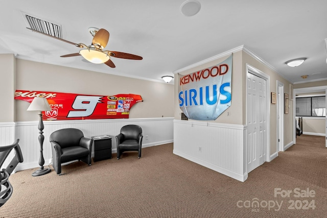 living area with carpet, visible vents, crown molding, and wainscoting