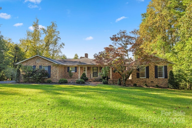 ranch-style home with a front yard, a chimney, brick siding, and crawl space