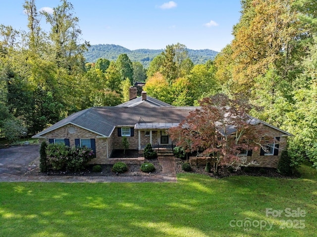 rear view of property featuring a yard, a view of trees, and a chimney