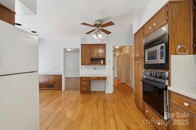 kitchen featuring stainless steel microwave, oven, light hardwood / wood-style flooring, ceiling fan, and white fridge