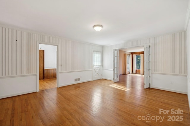 empty room with light hardwood / wood-style floors and ornamental molding