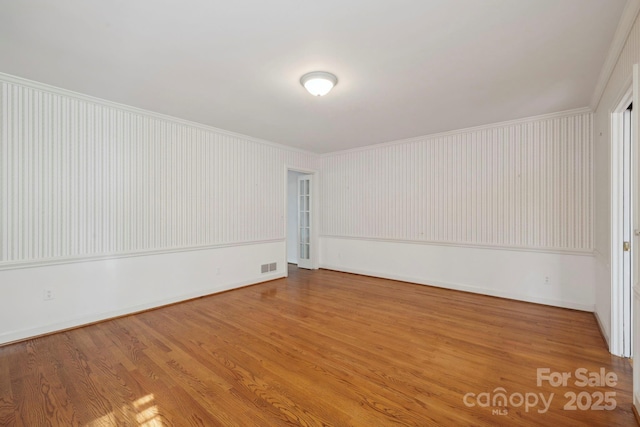 unfurnished room with hardwood / wood-style flooring and ornamental molding