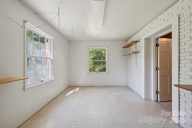 unfurnished room featuring brick wall