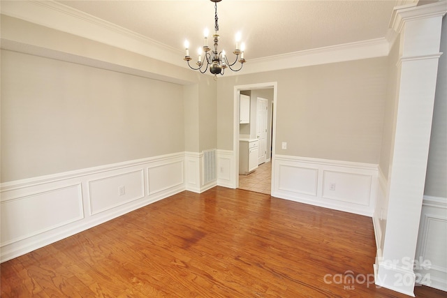 empty room featuring ornamental molding, a chandelier, and light hardwood / wood-style floors