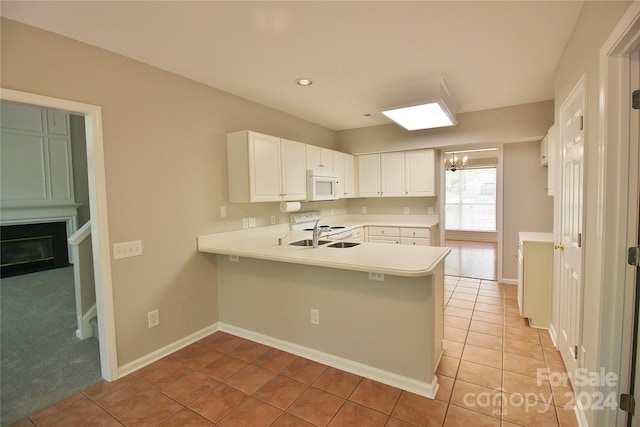 kitchen with white cabinets, white appliances, kitchen peninsula, sink, and light tile patterned flooring