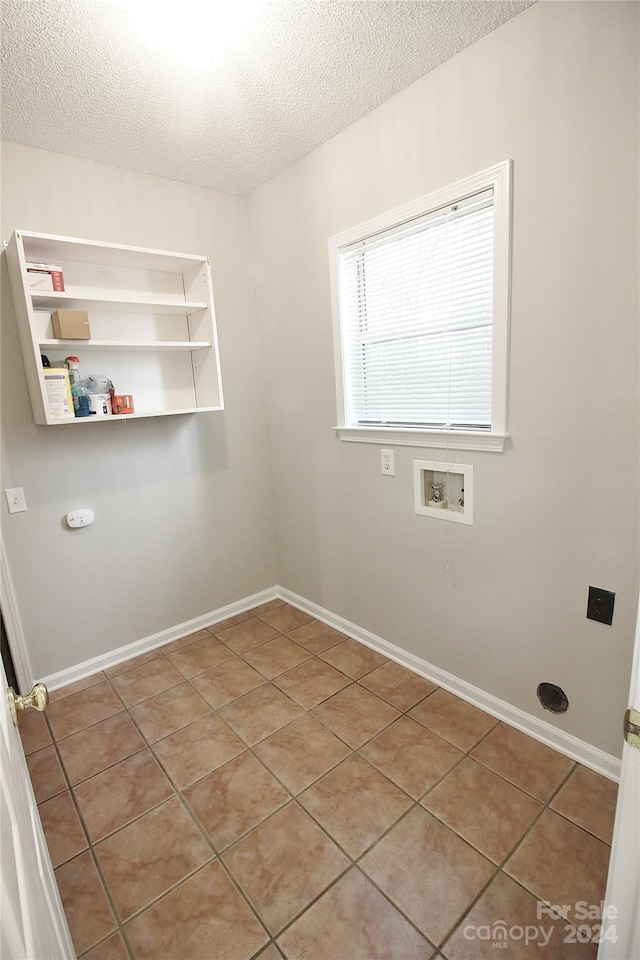 washroom with washer hookup, light tile patterned floors, and a textured ceiling