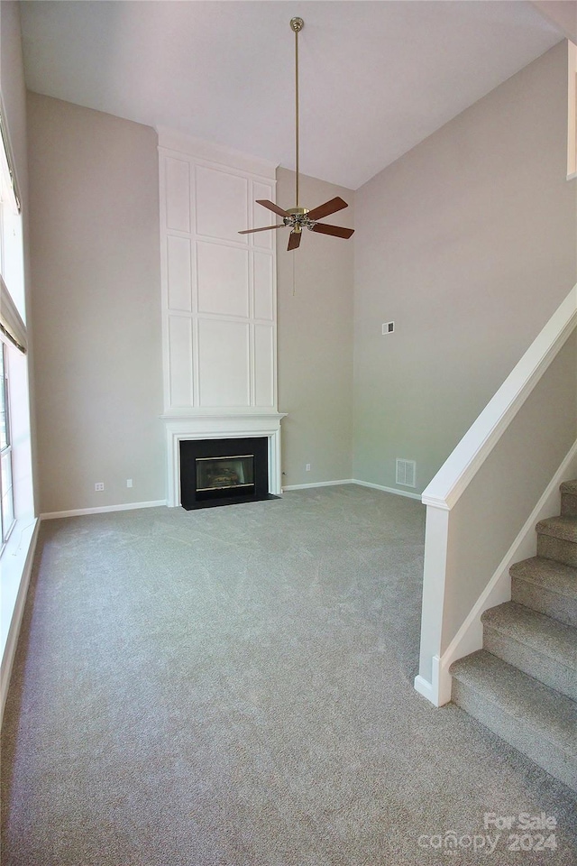 unfurnished living room featuring carpet flooring and ceiling fan