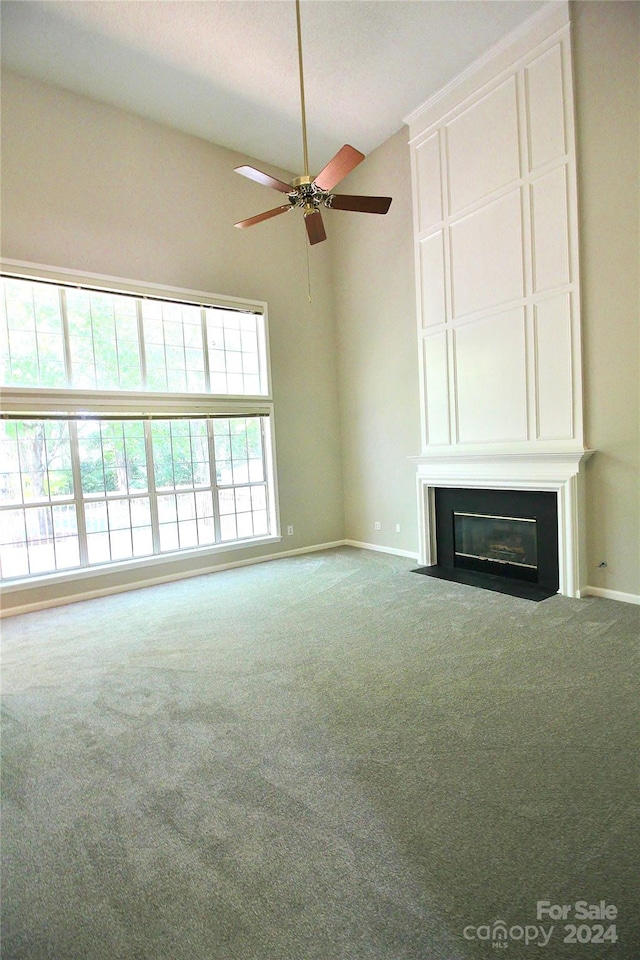 unfurnished living room featuring a high ceiling, ceiling fan, and carpet