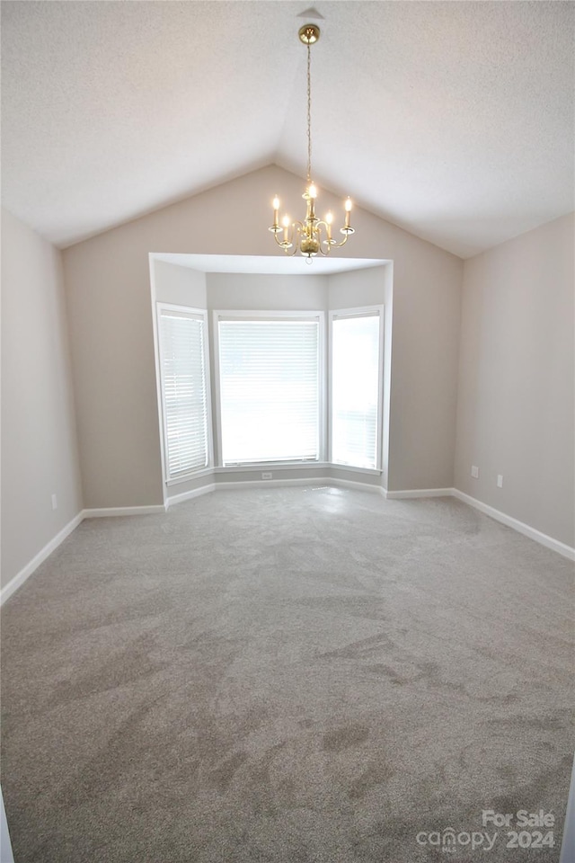 carpeted spare room featuring lofted ceiling, a notable chandelier, and a textured ceiling