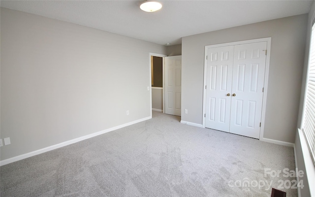 unfurnished bedroom featuring light colored carpet and a closet