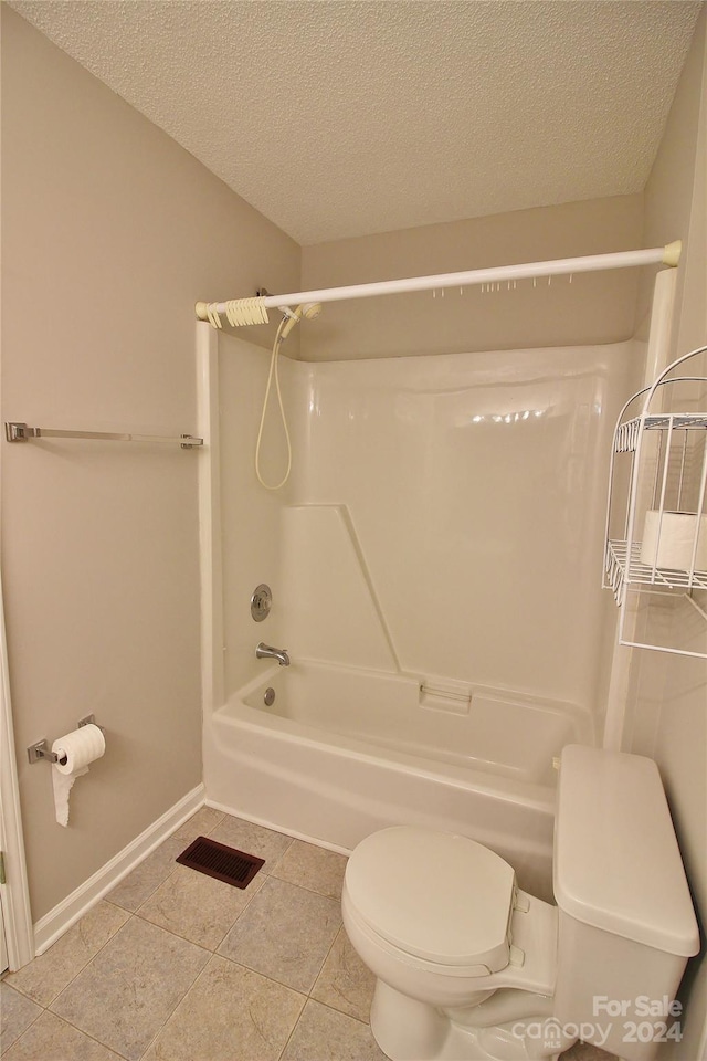 bathroom featuring a textured ceiling, toilet, bathtub / shower combination, and tile patterned flooring