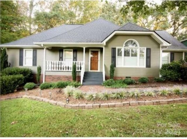 ranch-style home featuring covered porch and a front lawn