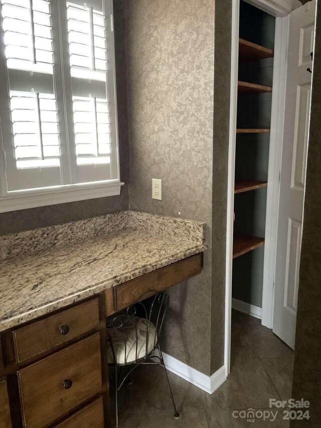 unfurnished office featuring built in desk and dark tile patterned floors