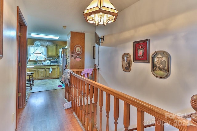 hallway with an inviting chandelier and light hardwood / wood-style floors