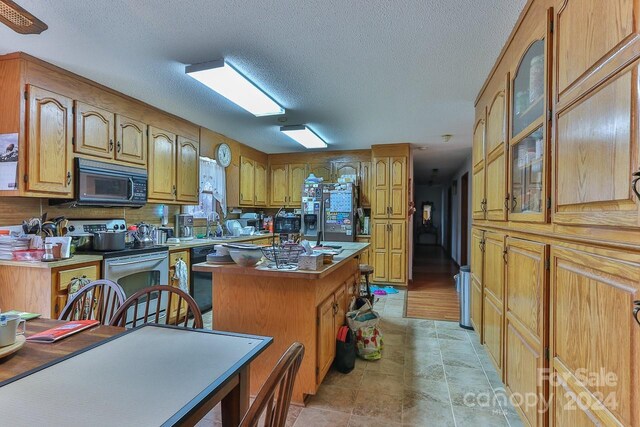 kitchen featuring a textured ceiling, a center island, and stainless steel appliances