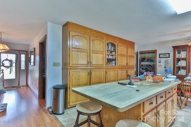 kitchen featuring a kitchen bar, a textured ceiling, a kitchen island with sink, and light hardwood / wood-style flooring