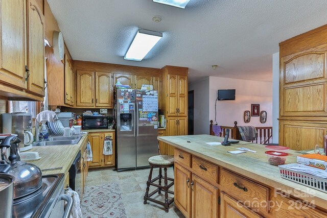 kitchen featuring stainless steel refrigerator with ice dispenser, a textured ceiling, and sink