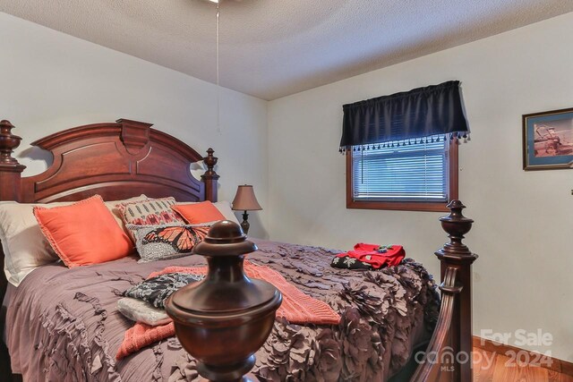 bedroom with a textured ceiling and hardwood / wood-style floors