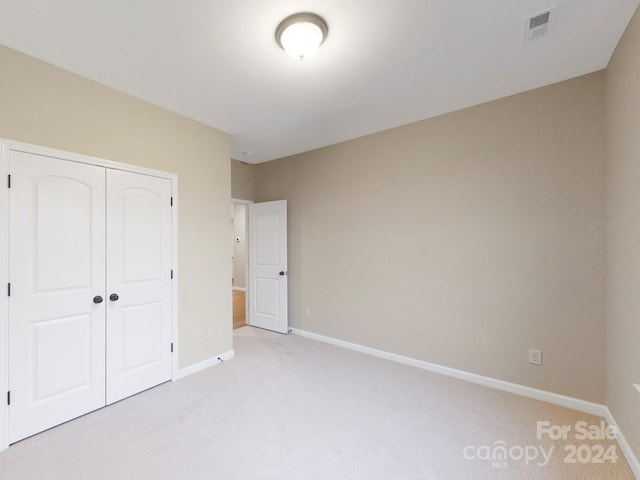 unfurnished bedroom with a closet and light carpet