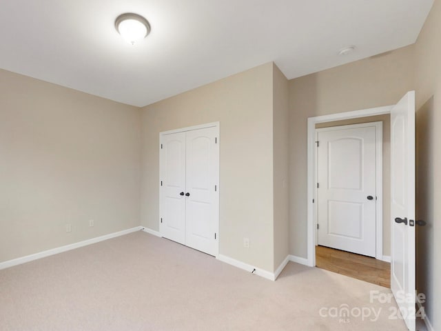 unfurnished bedroom with light colored carpet and a closet