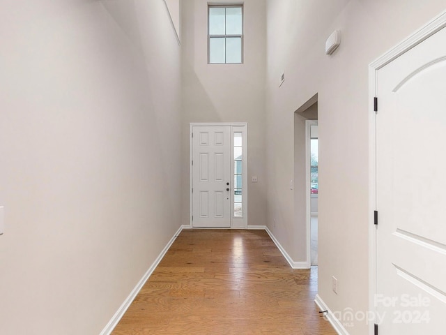 entrance foyer with light hardwood / wood-style floors and a towering ceiling