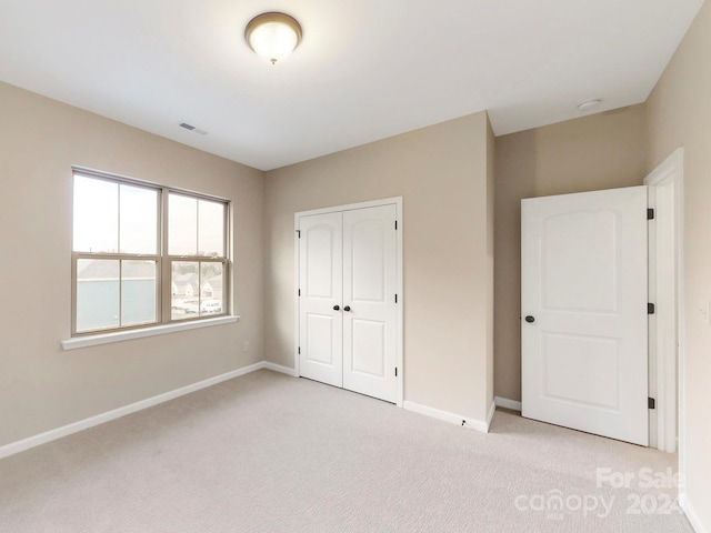 unfurnished bedroom featuring a closet and light colored carpet