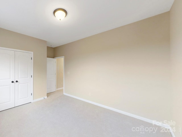 unfurnished bedroom with light carpet and a closet