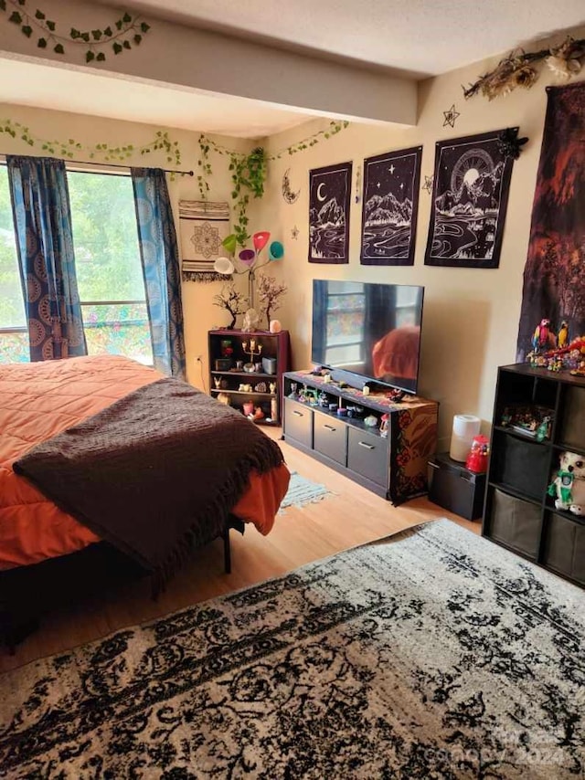 bedroom with hardwood / wood-style floors and beamed ceiling