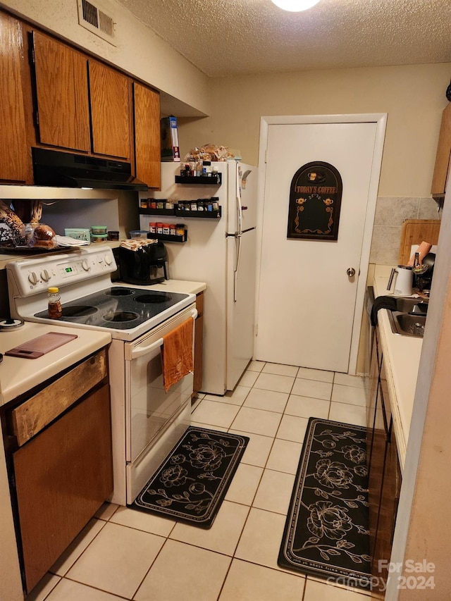 kitchen with exhaust hood, a textured ceiling, white appliances, and light tile patterned flooring