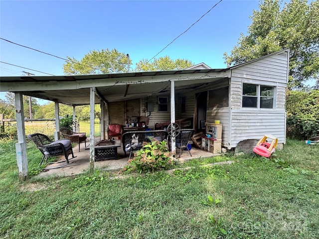 back of house with a patio area, a lawn, and an outdoor fire pit