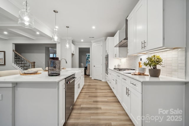 kitchen with white cabinets, stainless steel appliances, tasteful backsplash, an island with sink, and hanging light fixtures