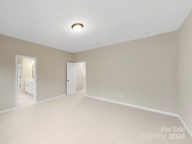 unfurnished bedroom with connected bathroom and light colored carpet