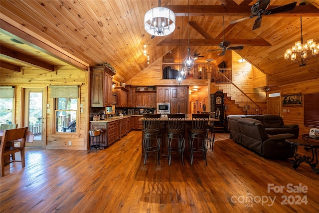 kitchen featuring wooden walls, dark hardwood / wood-style floors, beamed ceiling, and pendant lighting