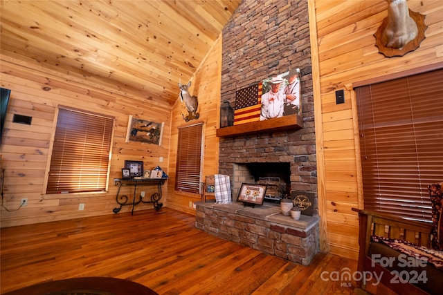 unfurnished living room featuring wood ceiling, wooden walls, high vaulted ceiling, a fireplace, and hardwood / wood-style floors