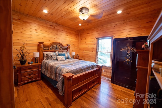 bedroom with wooden ceiling, wooden walls, and light hardwood / wood-style flooring