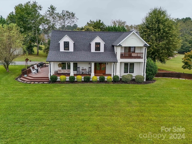 view of front of home with a patio, roof with shingles, a balcony, and a front yard