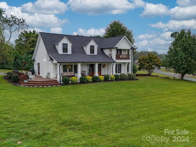 cape cod-style house with a shingled roof, stucco siding, a front lawn, and a balcony