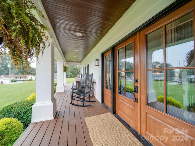 wooden deck with a porch and a lawn