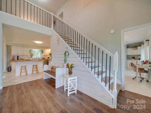 stairway with wood-type flooring, sink, and a high ceiling