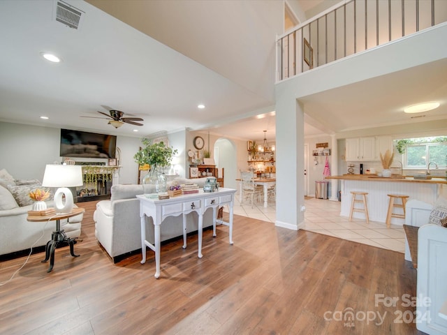 living area with visible vents, a fireplace, recessed lighting, light wood-style flooring, and ceiling fan with notable chandelier