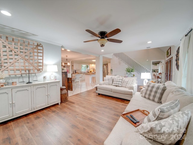 living room featuring ceiling fan with notable chandelier and light hardwood / wood-style flooring