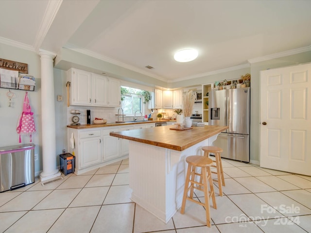 kitchen featuring stainless steel fridge, white cabinetry, decorative columns, a center island, and wood counters