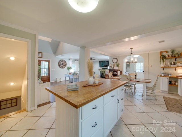 kitchen with white cabinets, butcher block countertops, ornamental molding, and light tile patterned floors