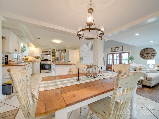 dining area with light tile patterned flooring, ornamental molding, sink, french doors, and an inviting chandelier