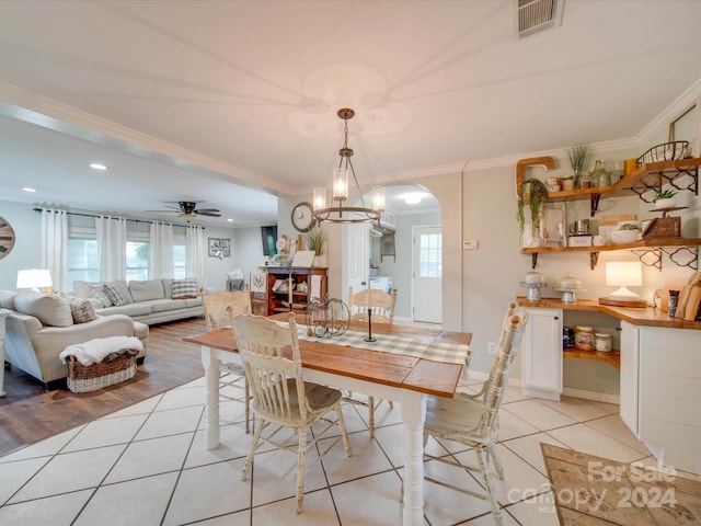 dining room with ceiling fan with notable chandelier, light hardwood / wood-style flooring, a healthy amount of sunlight, and crown molding